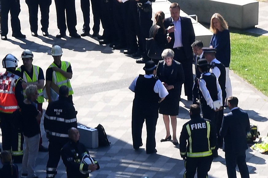 epa06029064 Prime Minister Theresa May (C) speaks with police at the scene of the fire that broke out at Grenfell Tower, a 24-storey apartment block in North Kensington, London, Britain, 15 June 2017. ...