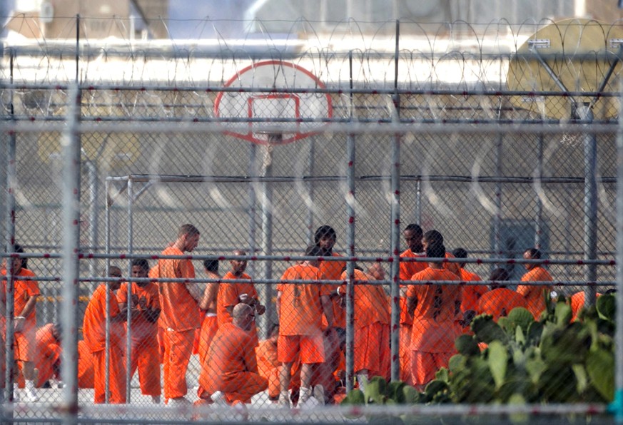 FILE - In this July 4, 2015 file photo, prison inmates stand in the yard at Arizona State Prison-Kingman in Golden Valley, Ariz. Arizona is severing ties with the private prison operator over what the ...