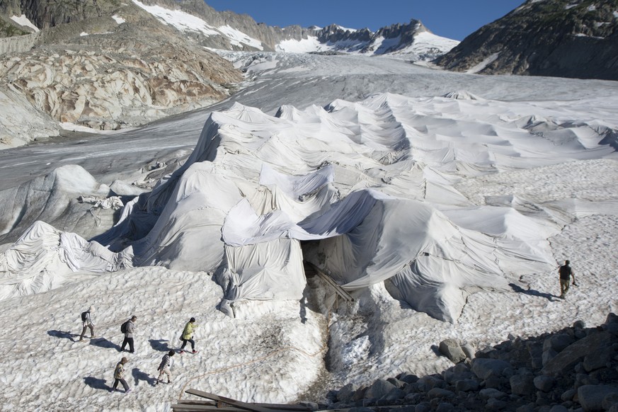 Touristen besuchen die Gletscher Grotte im mit Flies abgedeckten Gletscher das Ende des Rhonegletscher oberhalb von Gletsch am Furkapass am Dienstag 19. Juli 2016. (KEYSTONE/Urs Flueeler)