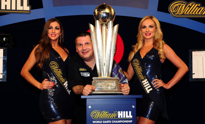 LONDON, ENGLAND - JANUARY 03: Gary Anderson of Scotland celebrates with the Sid Waddell Trophy alongside the oche girls after defeating Adrian Lewis of England in the final match during Day Fifteen of ...