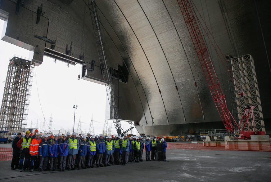 epa05278255 Workers of the Chernobyl nuclear power plant stand during the ceremony under the construction of a new protective shelter which will be placed over the remains of the nuclear reactor Unit  ...