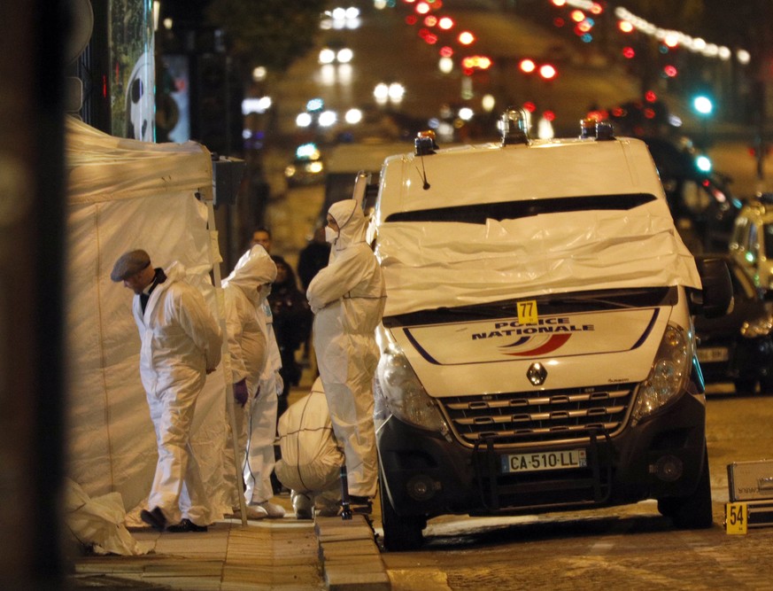 Forensic experts investigate the crime scene after a fatal shooting in which a police officer was killed along with an attacker on the Champs Elysees avenue in Paris, France, Friday, April 21, 2017. A ...