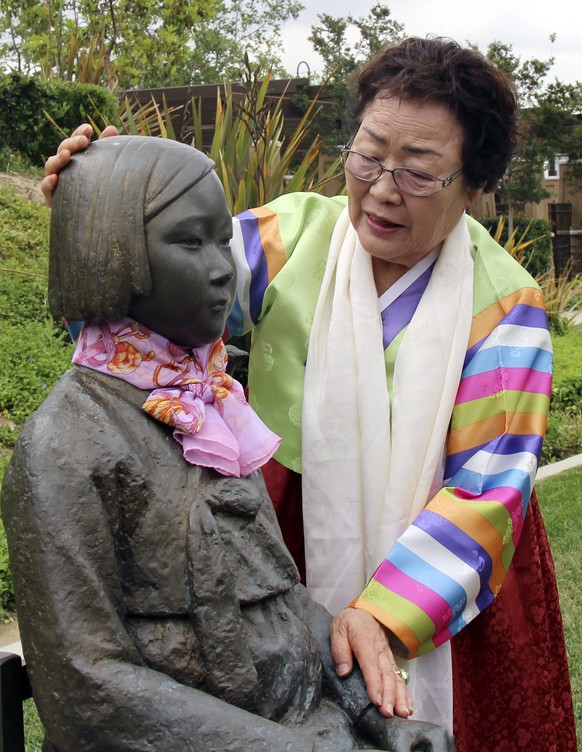 epa04736070 Lee Yong-soo, a former South Korean sex slave for Japan&#039;s World War II soldiers, touches a statue dedicated to the victims of Japan&#039;s wartime sex slavery as she visits a public l ...