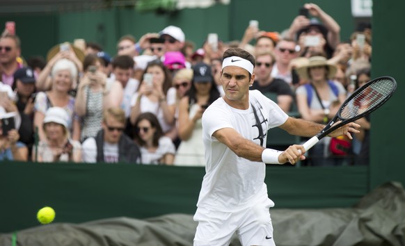 Tennis fans watch Roger Federer of Switzerland during a short training session prior to his first round match against Alexandr Dolgopolov of Ukraine, at the Wimbledon Championships at the All England  ...