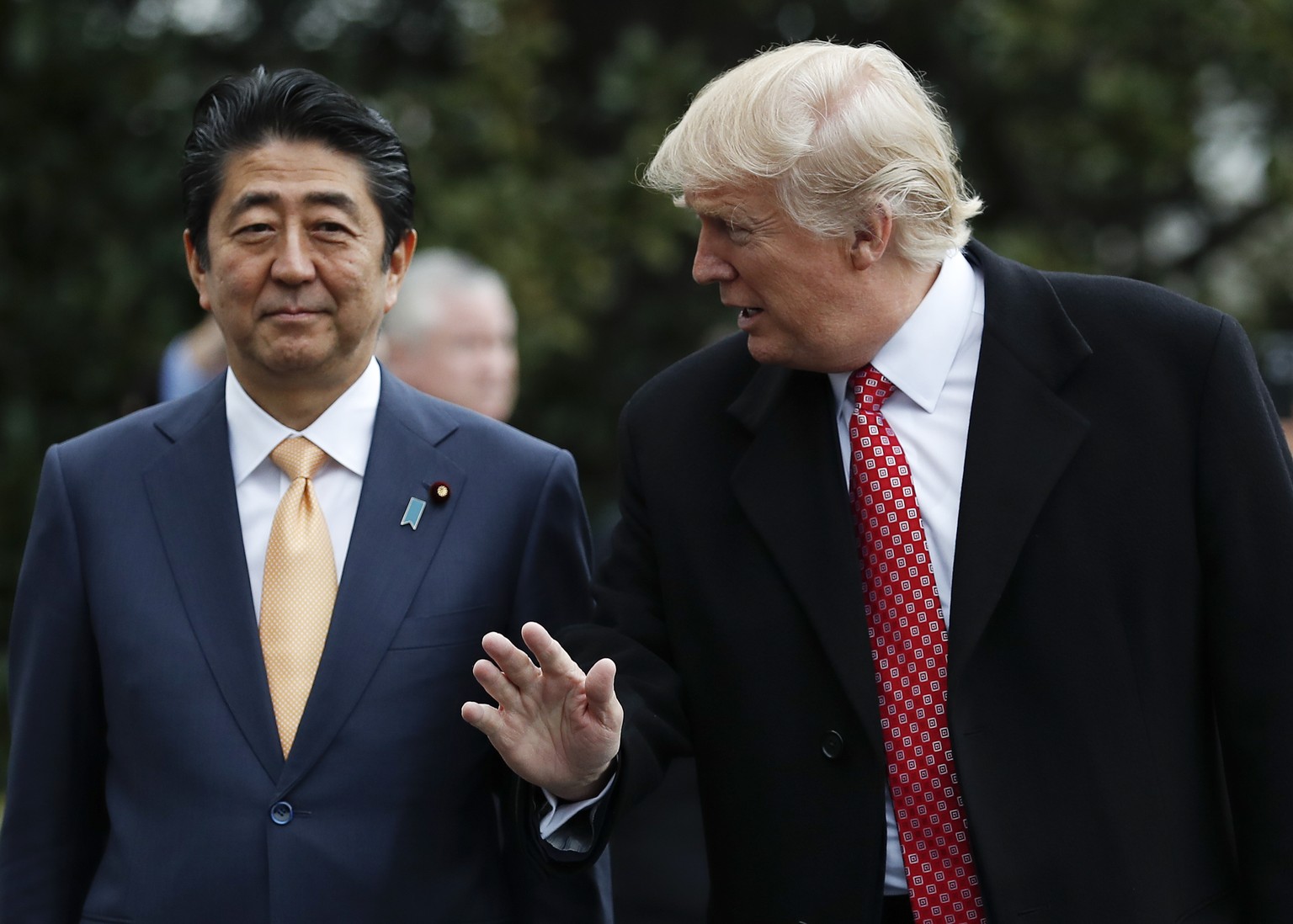 President Donald Trump talks to Japanese Prime Minister Shinzo Abe as they pause before boarding Marine One on the South Lawn of the White House in Washington, Friday, Feb. 10, 2017, for the short tri ...