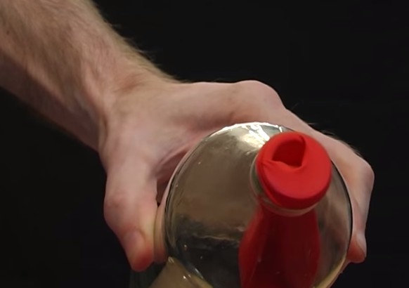 Stopf den Ballon in die Flasche und stülpe den vorderen Teil über den Flaschenrand. Dann bitte deinen Freund, ihn aufzublasen. 