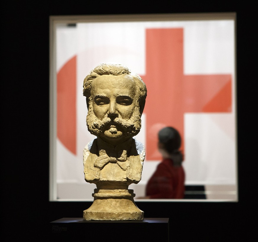 A visitor passes by the ICRC (International Committee of the Red Cross) emblem behind a bust of Henri Dunant, founder of the Red Cross, during a preview of the exhibition &quot;Humanizing War? The ICR ...