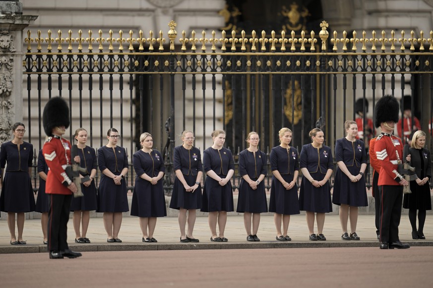 Buckingham Palace staff stand outside its gates during Queen Elizabeth II funeral ceremonies in central London Monday, Sept. 19, 2022. The Queen, who died aged 96 on Sept. 8, will be buried at Windsor ...