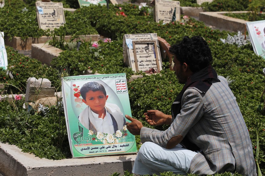 epa05345243 A Yemeni sits nearby the grave of Yemeni child Bilal al-Asadi who was killed in a Saudi-led airstrike hit his family house, on International Day of Innocent Child Victims of Aggression, in ...