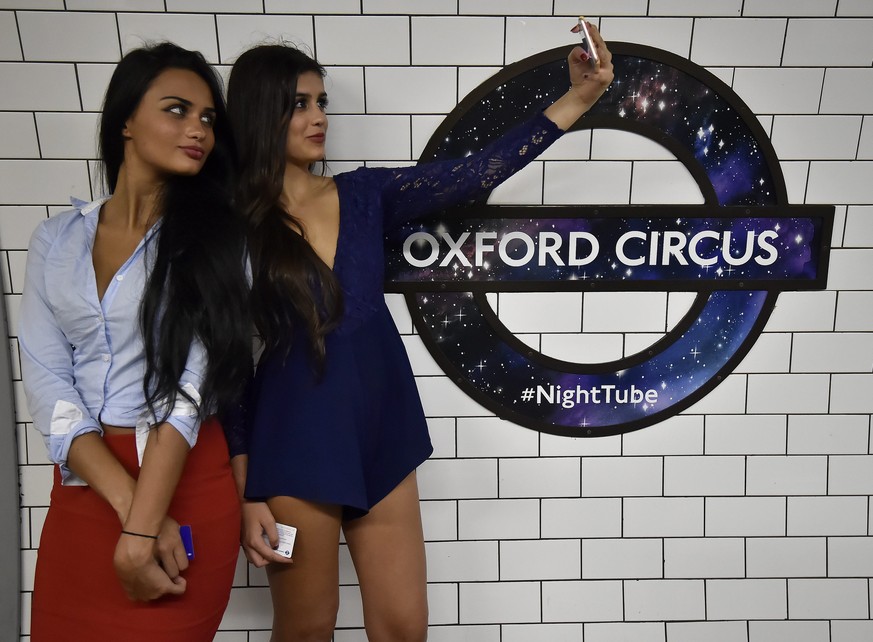 epa05501443 Tube passengers take a selfie next to a London underground roundel designed for the launching of the Night Tubes on display at Oxford Circus underground station in London, Britain, 19 Augu ...