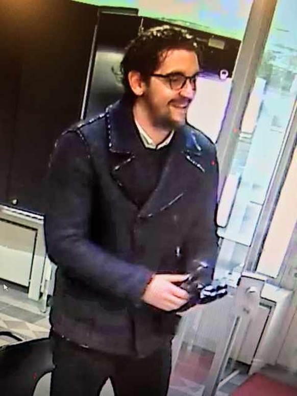 Täter 1 hat rötliche Haare, trug eine Brille und einen kleinen Bart sowie einen auffälligen Anzug aus blauem Stoff mit Noppen.