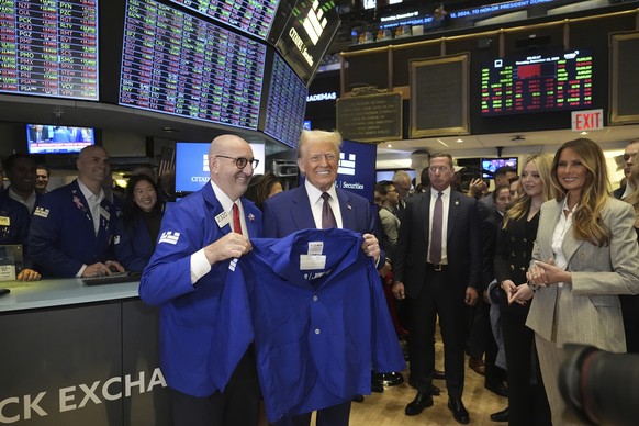 Nachrichten Linkding President-elect Donald Trump is handed a coat by trader Peter Giacchi, as he walks the floor of the New York Stock Exchange, Thursday, Dec. 12, 2024, in New York, as Melania Trump, right, looks on. (A ...