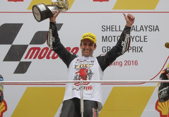 Moto2 winner Johann Zarco of France, center, celebrates with a trophy as second-placed Franco Morbidelli of Italy, left, and third-placed Jonas Folger of Germany applaud during the award ceremony for  ...