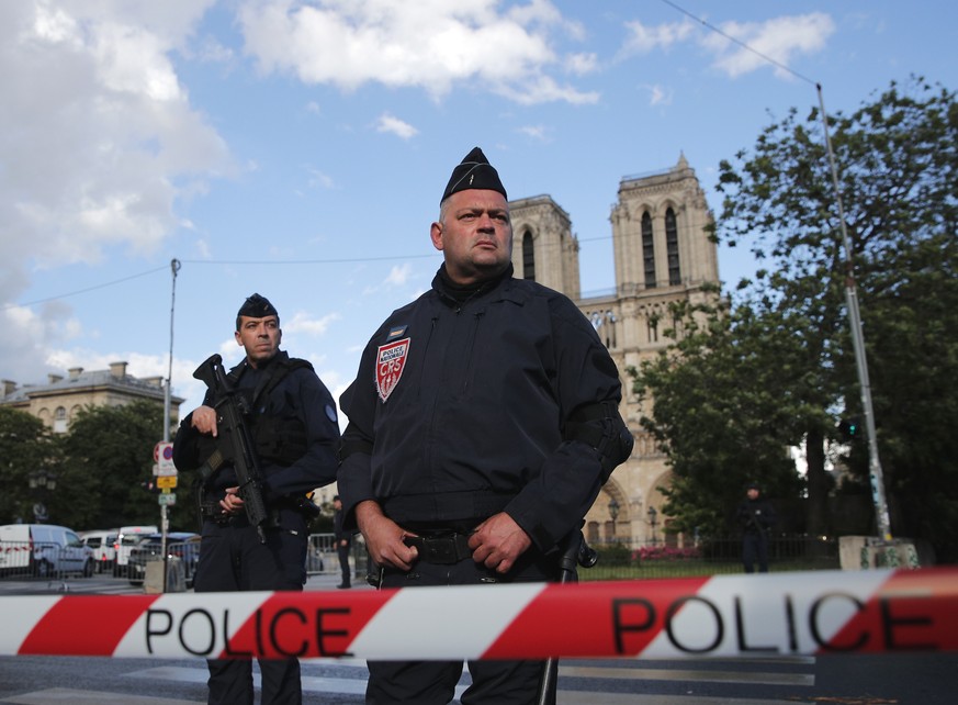 Police officers seal off the access to Notre Dame cathedral, seen in the background, after a man attacked officers with a hammer outside the famous landmark, in Paris, France, Tuesday, June 6, 2017. T ...