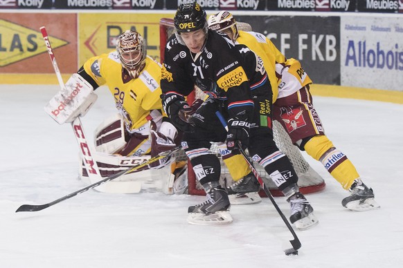 Fribourgs Stuermer Killian Mottet, Mitte, Servettes Torhueter Robert Mayer, links, und Servettes Stuermer Daniel Rubin, rechts, kaempfen um den Puck, beim Eishockey Meisterschaftsspiel der National Le ...