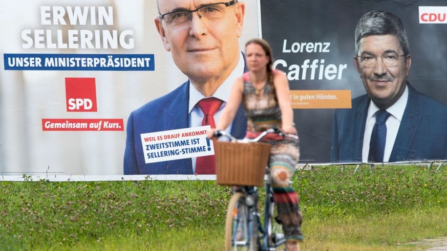 Eine Frau radelt am 30.08.2016 in Schwerin (Mecklenburg-Vorpommern) an zwei Großflächen-Wahlplakaten mit den Fotos der Spitzenkandidaten Erwin Sellering (l) von der SPD und Lorenz Caffier (r) von der  ...