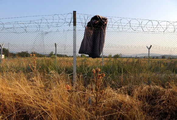 A sleeping bag hangs on a fence after the evacuation of refugees and migrants from a makeshift camp at the Greek-Macedonian border near the village of Idomeni, Greece, August 10, 2016. REUTERS/Alexand ...