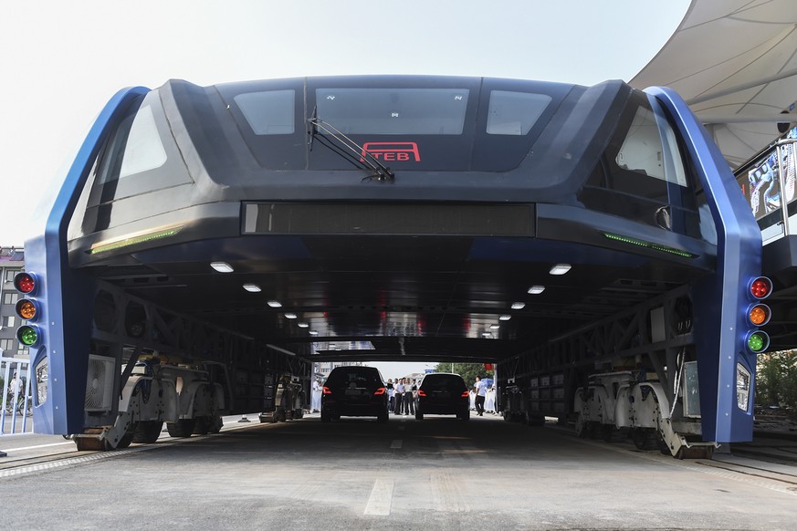 In this Tuesday, Aug. 2, 2016 photo released by Xinhua News Agency, people look at the Transit Elevated Bus TEB-1 run past vehicles as they conducted a test run in Qinhuangdao, north China&#039;s Hebe ...