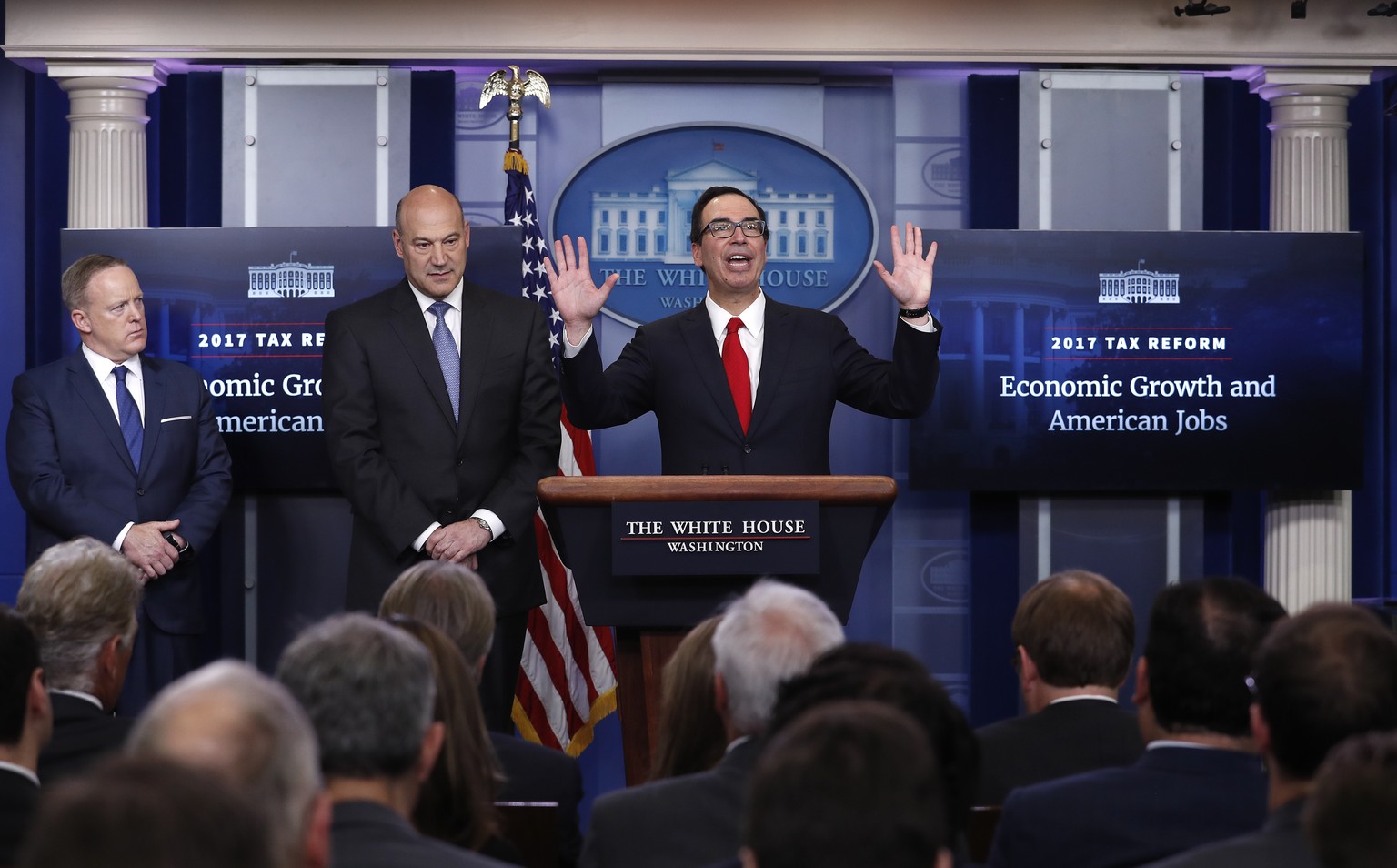 Treasury Secretary Steven Mnuchin, center, joined by National Economic Director Gary Cohn, center, and White House press secretary Sean Spicer speaks in the briefing room of the White House in Washing ...