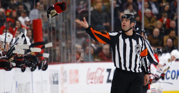 OTTAWA, ON - JANUARY 19: Referee Stephane Auger (15) throws a glove back towards the bench after a fight in a game between the Chicago Blackhawks and the Ottawa Senators at Scotiabank Place on January ...