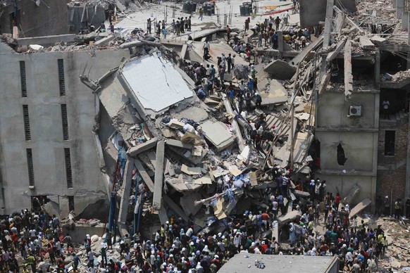 People rescue garment workers trapped under rubble at the Rana Plaza building after it collapsed, in Savar, 30 km (19 miles) outside Dhaka in this April 24, 2013 file photo. Protesters and family memb ...