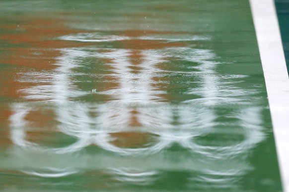 epa05471705 A reflection of the Olympic Rings logo on the net as Center Court is covered with puddles during a rain delay at the Olympic Tennis Center in Rio de Janeiro, Brazil, 10 August 2016. Rio 20 ...