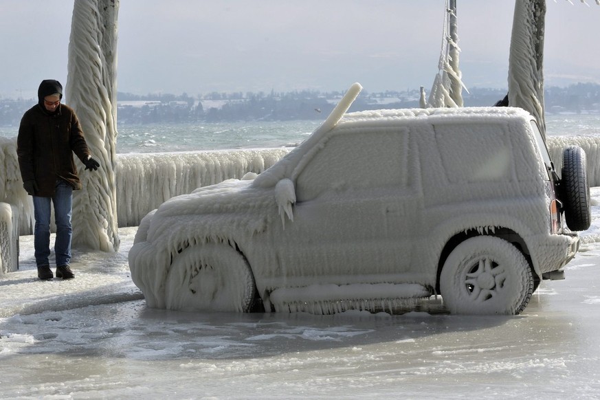 Une personne observe une voiture recouvert de glace, une bise tempetueuse a cree de somptueuses sculptures de glace au bord du lac Leman dans la region de Versoix pres de Geneve, ce samedi 4 fevrier 2 ...
