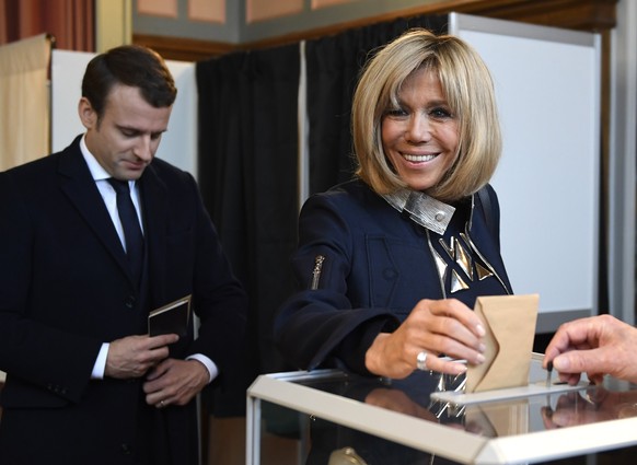 epa05947760 French presidential election candidate for the &#039;En Marche!&#039; (Onwards!) political movement, Emmanuel Macron (L) looks on as his wife Brigitte Trogneux (R) casts her ballot at a po ...