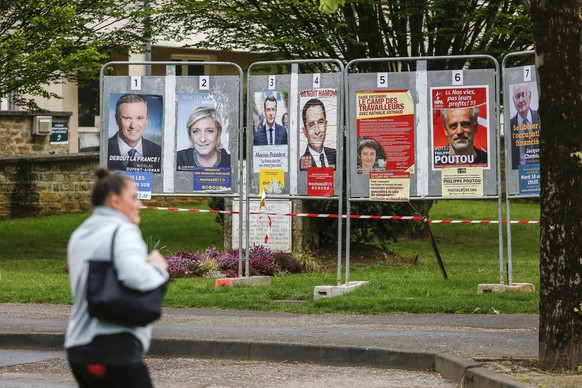 epa05908737 A woman passes by in front of a selection of official election campaign posters of candidates for the 2017 French presidential election, in Sedan, France, 15 April 2017. The French preside ...