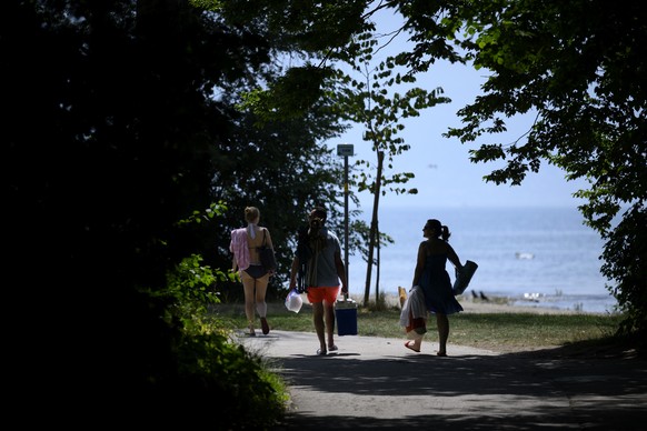 People cooling off in the shade of trees during warm weather on the shore of the Lake Geneva at the Vidy beach (plage de Vidy), Sunday, June 19, 2022. People flocked to parks and pools across Western  ...