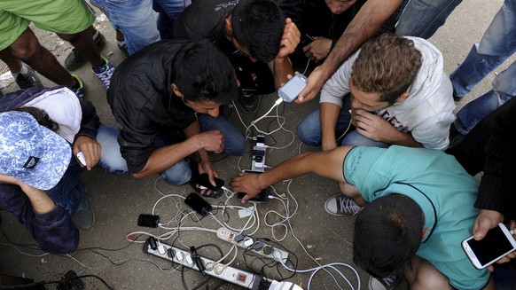 Refugees and migrants charge their mobile phones as they wait to cross the borders of Greece with Macedonia, near the village of Idomeni, September 6, 2015. Greece is struggling to cope with the hundr ...