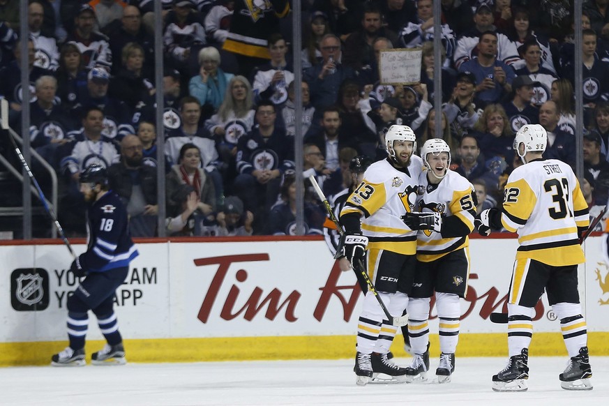 Winnipeg Jets&#039; Bryan Little (18) skates past as Pittsburgh Penguins&#039; Nick Bonino (13), Jake Guentzel (59) and Mark Streit (32) celebrate Bonino&#039;s third goal of the night, during the sec ...