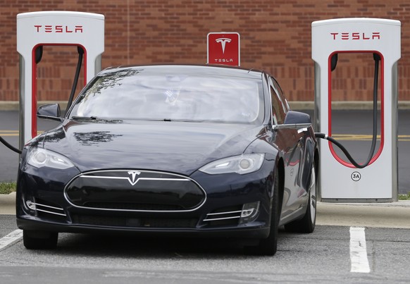 In this Saturday, June 24, 2017, photo, a Tesla car recharges at a charging station at Cochran Commons shopping center in Charlotte, N.C. On Monday, July 3, 2017, Tesla CEO Elon Musk sent out a tweet  ...