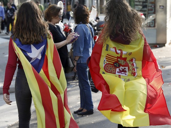 epa06242610 A girl with a &#039;estelada&#039; flag and other with a Spanish flag walk towards the University square, in downtown Barcelona, northeastern Spain, 03 October 2017, to protest against the ...