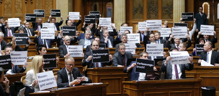 Mitglieder der SVP halten Plakate mit der Aufschrift &quot;Verfassungsbruch&quot; hoch, bei der Schlussabstimmung ueber die Masseneinwanderungsinitiative im Nationalrat, waehrend der Wintersession der ...