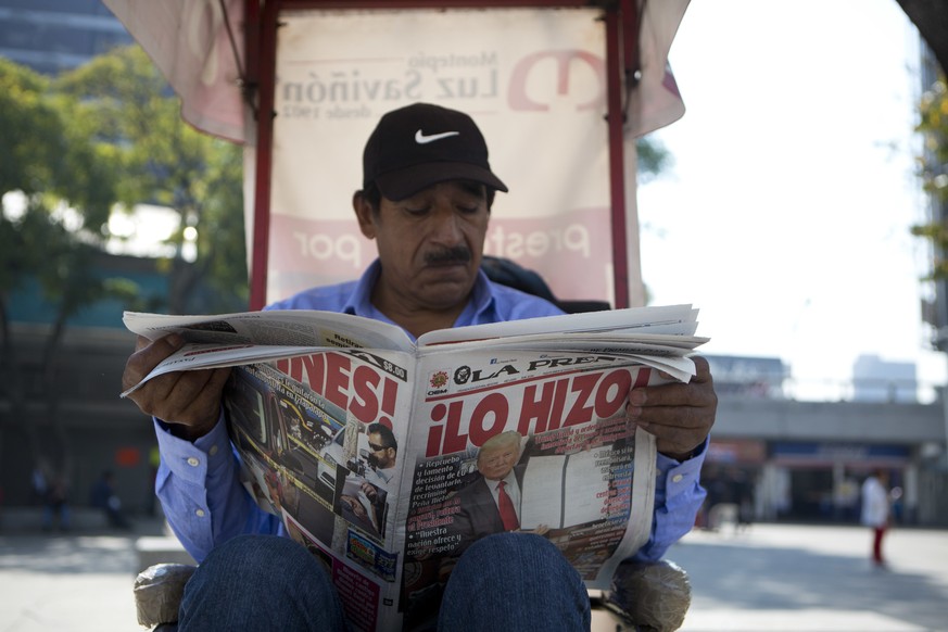 A man having his shoes shines reads a newspaper whose front page declares &quot;He did it!&quot; over a picture of U.S. President Donald Trump holding up signed documents, as he took action to jumpsta ...
