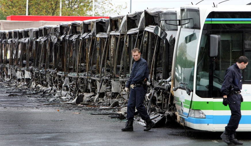 Polizisten untersuchen am 4. November 2005 in Trappes, westlich von Paris, die Wracks von insgesamt 27 ausgebrannten Autobussen. Die Naechte vom 27. Oktober bis zum 17. November vergangenen Jahres sin ...