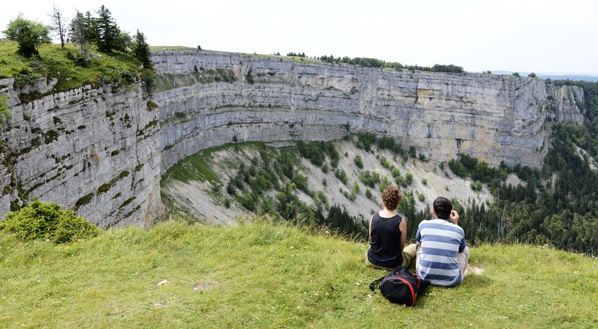 Ausfluegler geniessen die Aussicht zum Creux du Van, am Samstag, 19. Juli 2014, bei Noiraigue. Der Creux du Van im Schweizer Jura an der Grenze zwischen den Kantonen Neuenburg und Waadt ist etwa 1200  ...