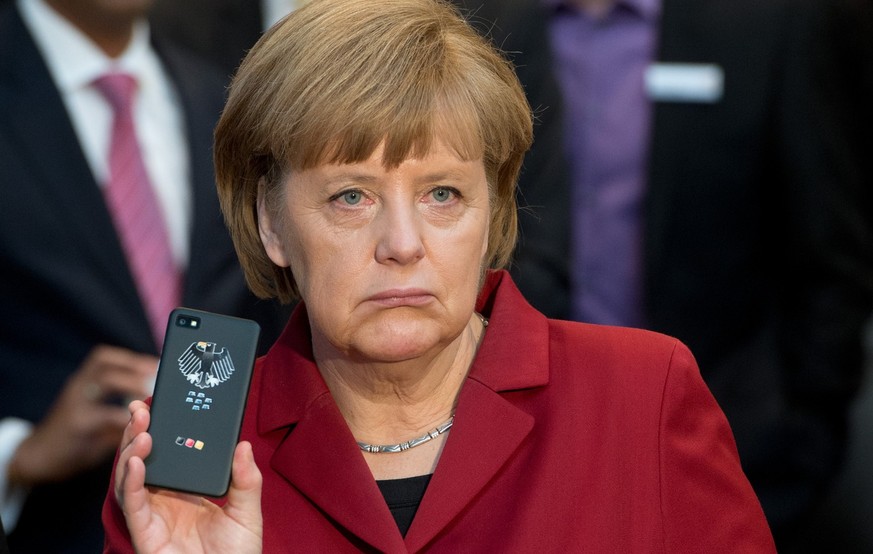 The March 5, 2013 photo shows German Chancellor Angela Merkel presenting a tap-proof mobile phone of Blackberry at a booth of Secusmart during the opening round tour of the world&#039;s largest comput ...