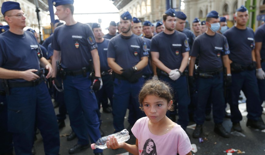 Polizei-Hundertschaften am Keleti-Bahnhof, im Vordergrund ein Flüchtlingsmädchen: Die ungarischen Behörden haben am Dienstagmorgen die Räumung des wichtigsten Budapester-Bahnhofs bekanntgegeben.