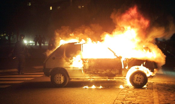 French riot police officers walk by a burning car in Bagnolet, Paris suburban, Tuesday Aug. 11, 2009, where an 18-year old youth worked, before dying in a motorbike accident while fleeing police Sunda ...