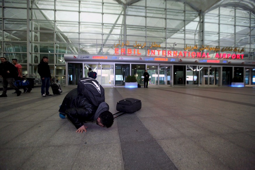 Ein irakischer Heimkehrer aus Deutschland küsst nach der Ankunft in Erbil den Boden (27.01.2016).