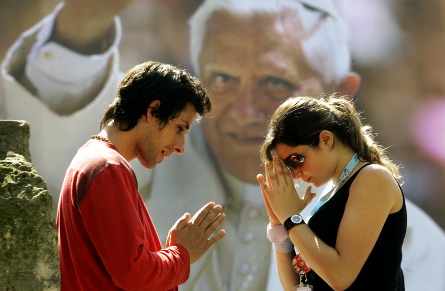 Florenzia und Ignazio, links, aus Argentinien beten vor einem Poster von Papst Benedikt XVI waehrend einer Wallfahrt waehrend des XX. Weltjugendtages in Koeln am Mittwoch, 17. August 2005. Bis zum 21. ...