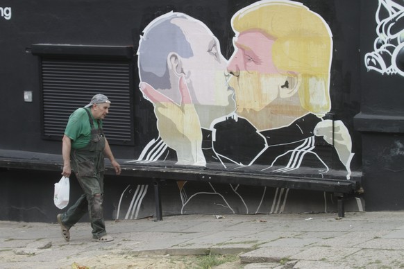 epa05455320 A man passes by a graffiti mural by Lithuanian artist Mindaugas Bonanu depicting US Republican presidential candidate Donald Trump (R) kissing Russian President Vladimir Putin on the wall  ...
