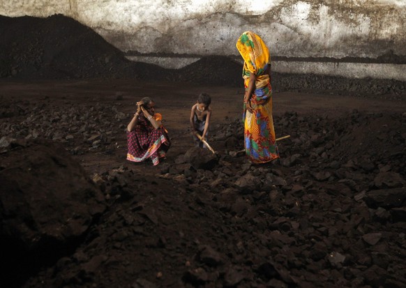Labourers rest as a boy playfully shovels coal at a yard in the western Indian city of Ahmedabad November 20, 2014. India will allow locally registered foreign firms to mine and sell coal when commerc ...