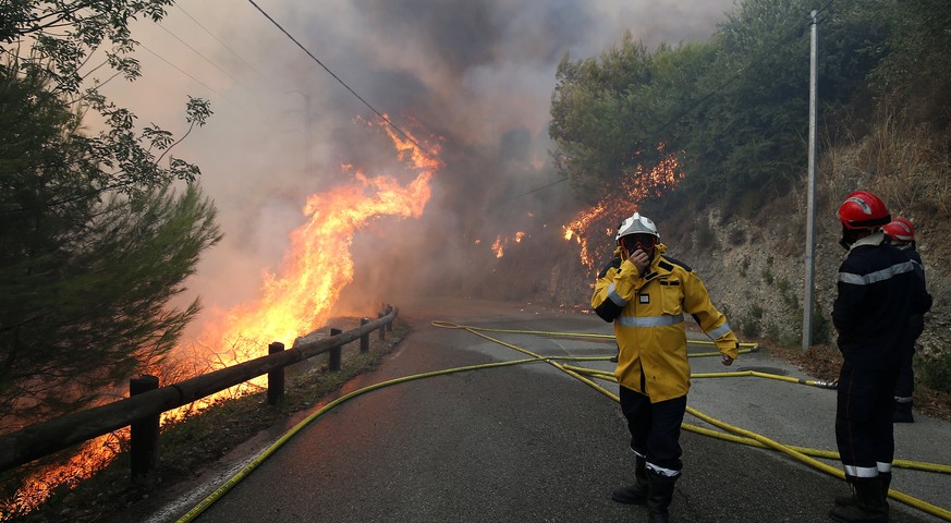 epaselect epa06093303 Firemen attend the scene of a forest fire in Castagniers near Nice, southern France, 17 July 2017. Large forest fires fueled by strong winds and dry weather are blazing in severa ...