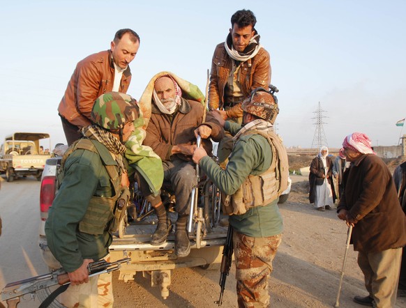 Kurdische Sicherheitskräfte nahe Kirkuk heben einen älteren Mann im Rollstuhl von einem Fahrzeug. Er war von den IS-Extremisten freigelassen worden.