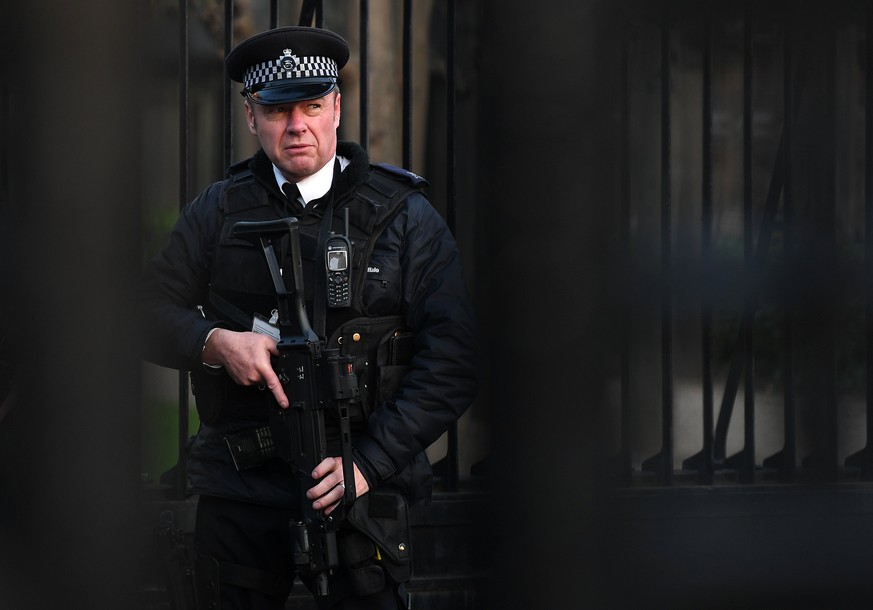 epa05868470 An armed policeman on guard behind the closed gates of Westminster Palace in London, Britain, 24 March 2017. Well-wishers have flocked to the scene of the 22 March terror attack to pay the ...