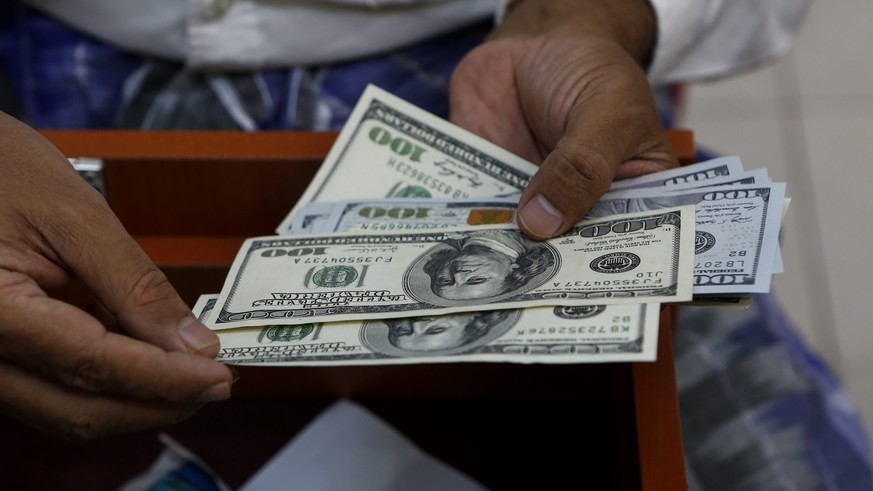 epa04984955 A man checks US dollar notes at a money exchange shop at downtown area in Yangon, Myanmar, 20 October 2015. Myanmar&#039;s central bank has announced to revoke the foreign-exchange license ...