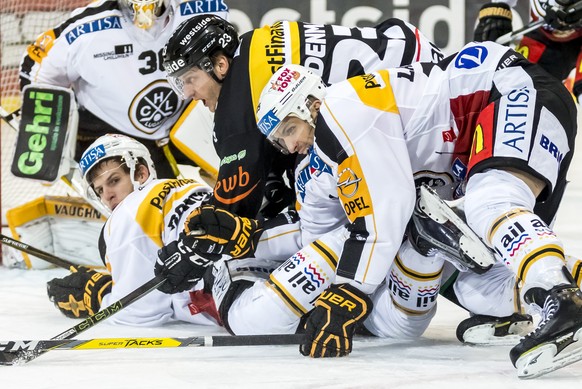 Simon Bodenmann, Mitte, von Bern, gegen Massimo Ronchetti, links, und Maxim Lapierre, rechts, von Lugano, im Kampf um den Puck im Eishockey Meisterschaftsspiel der National League A zwischen dem SC Be ...